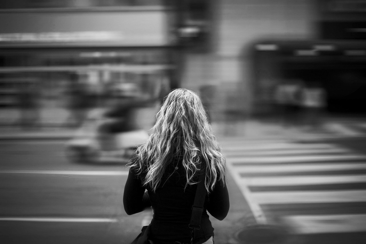 giovane donna di spalle davanti alle strisce pedonali