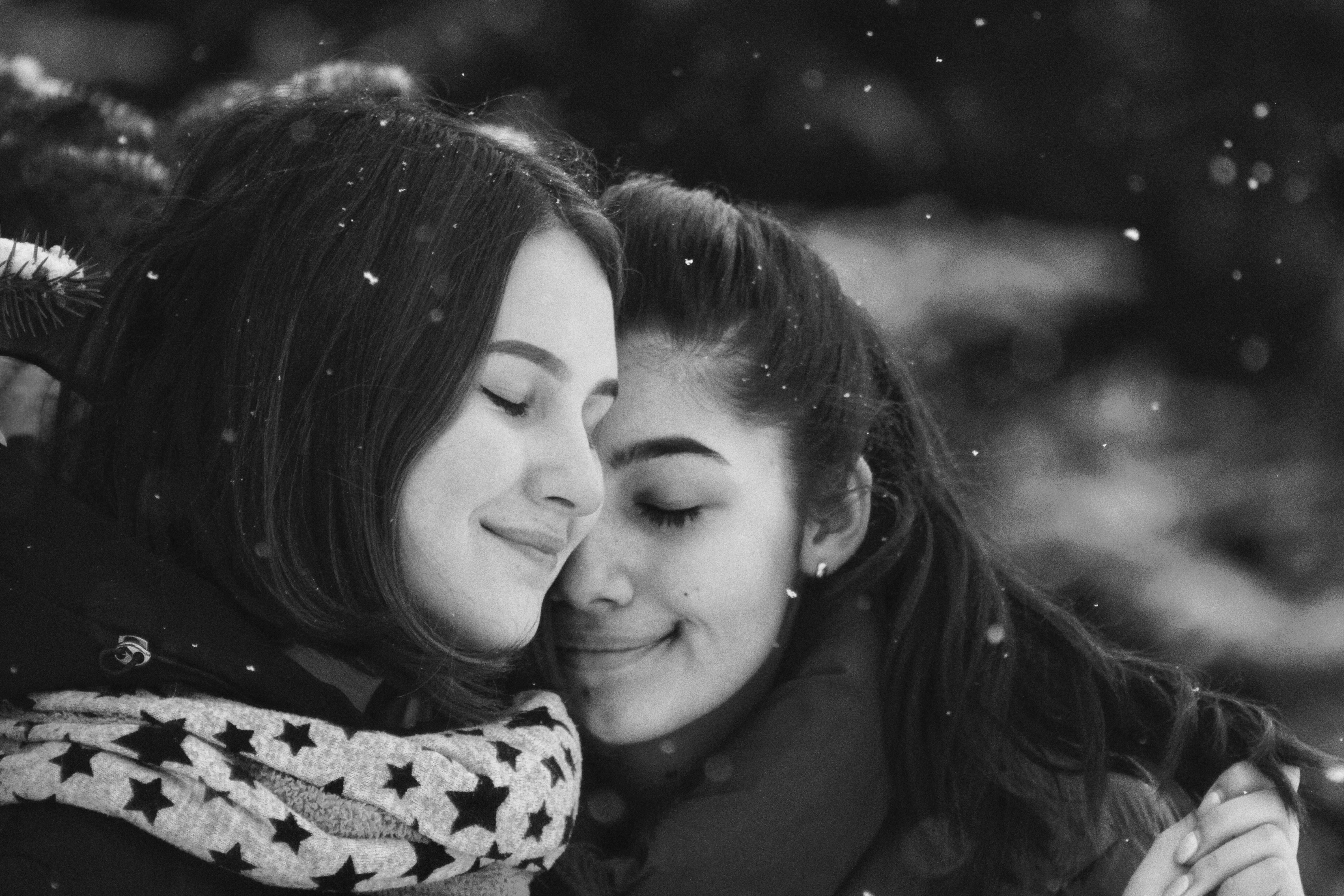 two women gently embracing with eyes closed, expressing comfort and emotional closeness