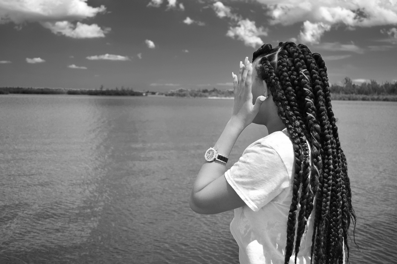 una ragazza con le freccine davanti al mare si tiene la testa con le mai aperte
