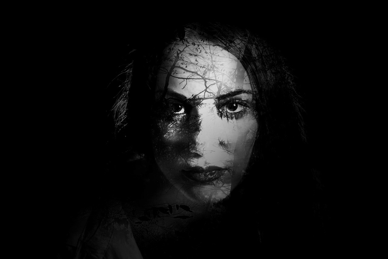 portrait of a woman’s face emerging from darkness, symbolizing introspection and mental overload
